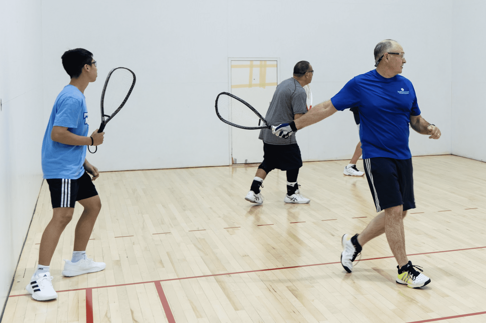 three adults playing racquetball